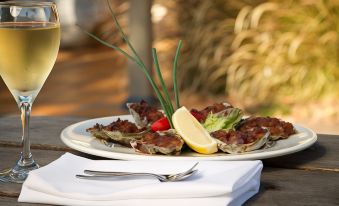 a dining table with a plate of oysters , a fork , and a glass of wine on it at Potters Apartments