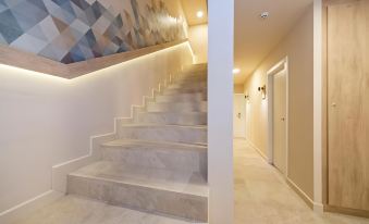 a white staircase with a wall decorated by geometric art , leading to another room on either side at Hotel Victori