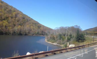 a scenic view of a lake surrounded by trees and mountains , with a road running alongside it at The Lancaster Motel