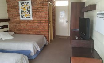 a bedroom with two beds , a television , and a door leading to another room , both covered in white sheets at Toora Lodge Motel