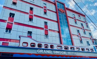 a large hotel building with a red and white exterior , located in a city setting at Grand Singgie Hotel
