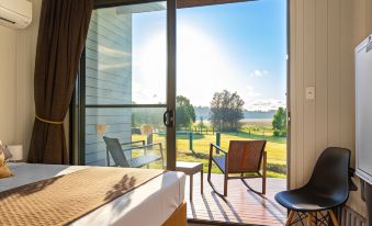 a bedroom with a bed and a chair is shown with a sliding glass door leading to a balcony at Narangba Motel (Formerly Brisbane North B&B and Winery)