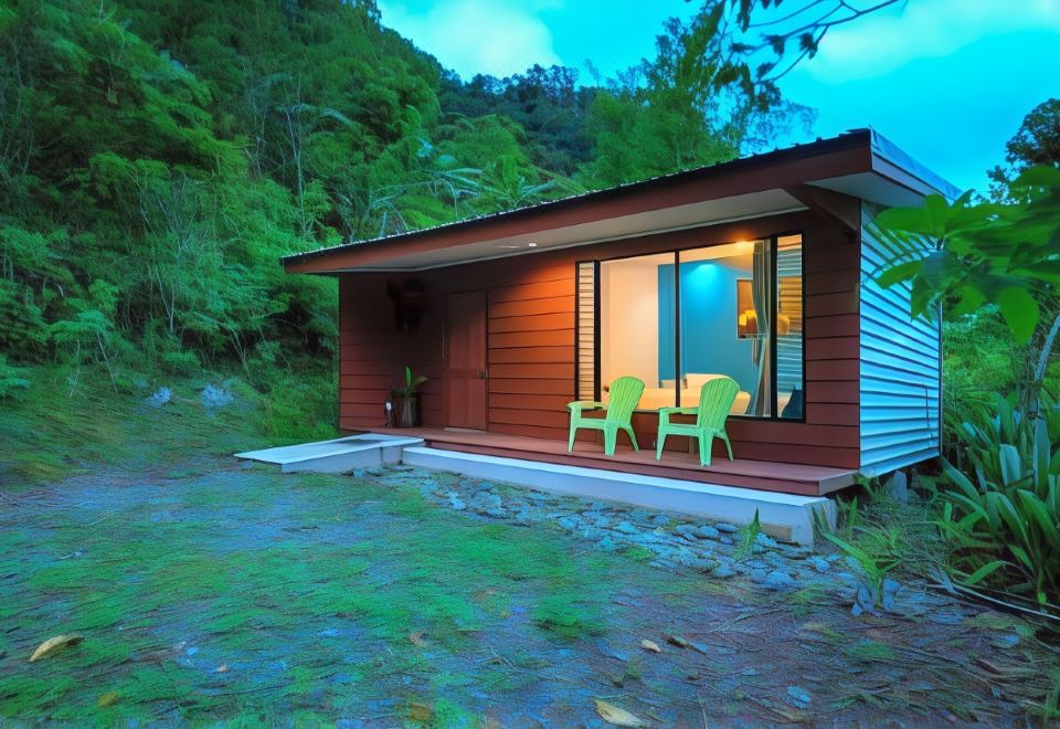 a small wooden house surrounded by green grass and trees , with two chairs placed outside the front door at Hotel Quelitales