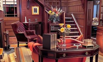 a room with a wooden staircase , red chairs , and a table with a vase of flowers at Copper Beech Inn