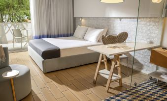 a modern hotel room with a bed , desk , and chair , along with a glass partition separating the sleeping area from the rest of the room at Tui Blue Makarska