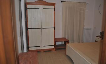 a bedroom with a wooden wardrobe , bed , and table , along with curtains and a window at Le Quattro Stagioni
