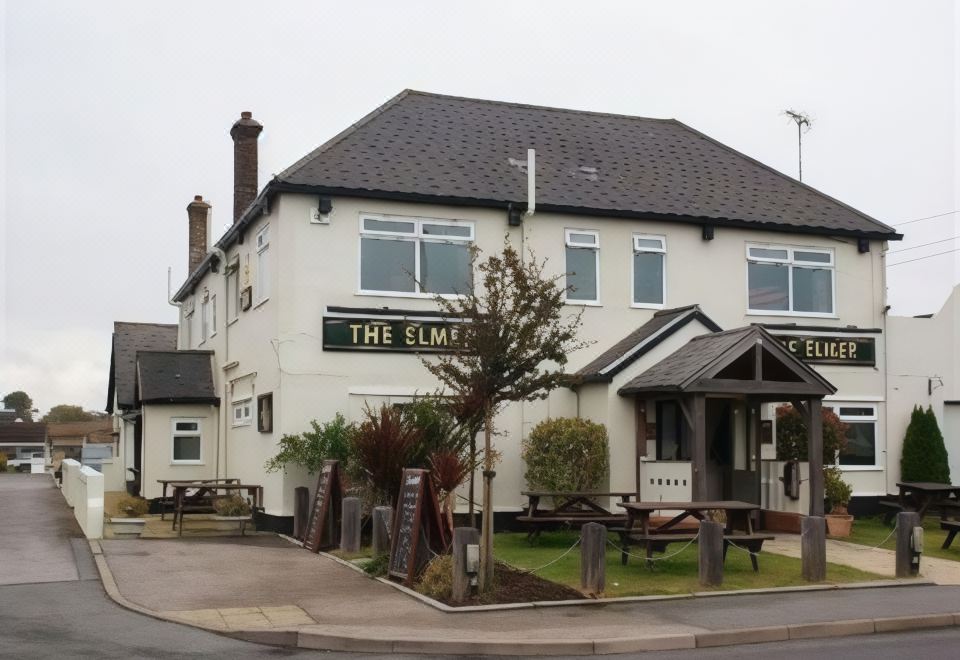 "a white building with a sign that says "" the elmer "" is surrounded by trees and benches" at The Elmer