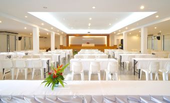 a large banquet hall with white tables and chairs , along with a stage and a podium at Chaolao Cabana Resort