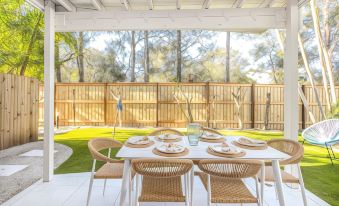 a patio with a white table and chairs , surrounded by a fence , is shown in the image at Hastings Cove Holiday Apartments