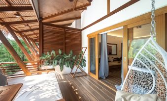 a modern , open - concept living space with wooden beams and a large window , featuring a balcony with a hammock and green plants at Siargao Island Villas