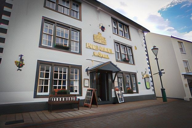 "a white building with a sign that says "" cafe karlin "" and a bench in front of it" at The Howard Arms