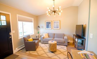 a cozy living room with a couch , two chairs , a coffee table , and a tv at Colony Suites
