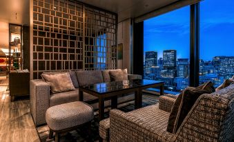 a modern living room with a large window overlooking a city skyline , providing a bright and inviting view of the surrounding area at The Royal Park Hotel Iconic Osaka Midosuji