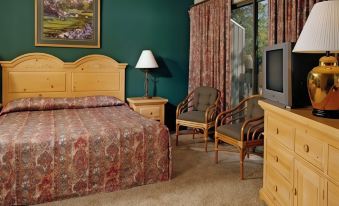 a cozy bedroom with a king - sized bed , two chairs , and a flat - screen tv mounted on the wall at Club Wyndham Resort at Fairfield Bay