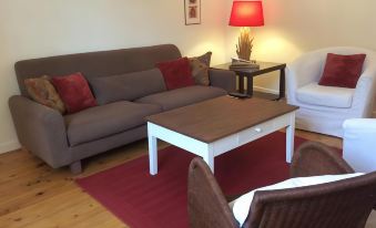 a cozy living room with a couch , a chair , a rug , and a lamp on a coffee table at La Terrasse, Centre St-Antonin