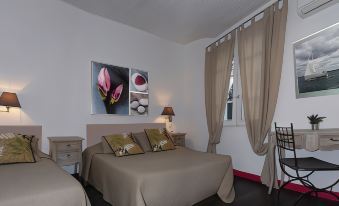 a bedroom with a bed , two lamps , and a window covered by beige curtains , featuring two pictures of flowers on the wall at Hotel Ermitage
