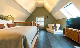 a bedroom with a sloped ceiling , a large bed , and a bathtub in the corner at The Collector