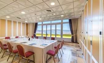 a large conference room with multiple tables , chairs , and a view of the ocean through large windows at Sercotel Hotel Bahia de Vigo