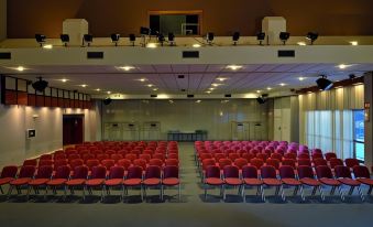 an empty auditorium with rows of red chairs and a stage at the front , ready for an event at Hotel l'Eden des Cimes - Vacances Bleues - Belle Plagne 2100