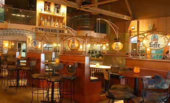 a restaurant with wooden tables and chairs , bar stools , and a large window overlooking the inside at Hotel Moco Valleyfield