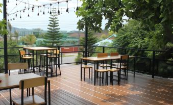 an outdoor dining area with several tables and chairs arranged on a wooden deck , surrounded by trees at Lam-Tong Resort
