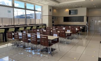 a large , empty conference room with multiple tables and chairs arranged in rows , ready for meetings or events at Toyoko Inn Meitetsu Chiryu Ekimae