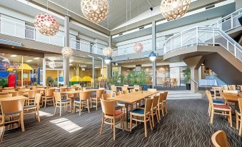 a modern restaurant with wooden tables and chairs , pendant lights hanging from the ceiling , and large windows at The Lighthouse Hotel