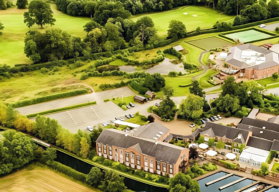 an aerial view of a large house surrounded by a lush green field , with a body of water in the background at Lion Quays Resort