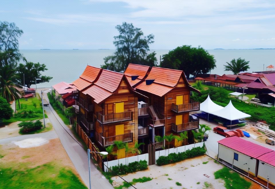 a wooden house with red roof and yellow windows is surrounded by trees and a body of water at Kampong Pinang Sebatang