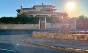 a driveway leading to a beautiful house , with the sun shining brightly in the background at Il Tramonto