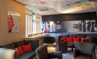 a modern lounge area with a black and brown color scheme , featuring comfortable seating arrangements and a large mural on the wall at Ibis Aéroport Bâle-Mulhouse