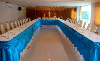 a large dining room with long tables covered in blue tablecloths , creating an elegant and festive atmosphere at That Phanom River View Hotel