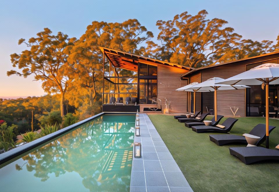a modern house with a swimming pool surrounded by lounge chairs and umbrellas , creating a relaxing atmosphere at Spicers Sangoma Retreat