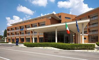 a modern building with an orange facade , green columns , and a large flag of the republic of ireland at Inn Naples Airport