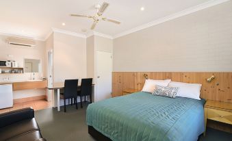 a bedroom with a bed , desk , and chairs is shown next to a dining area at Catalina Motel Lake Macquarie