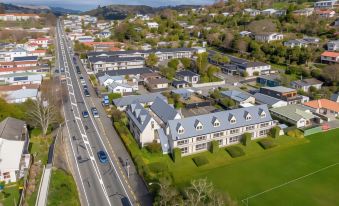 aerial view of a large building surrounded by trees and a road , with cars driving on the road at Admirals Motor Inn