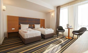 a hotel room with two beds , a desk , and a chair , all neatly arranged in a modern style at Hotel Avenue - Avenue Hotels