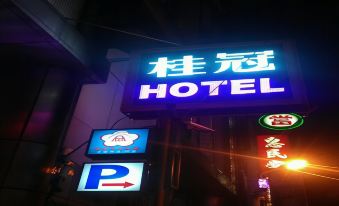 a nighttime scene of a hotel sign in a city , illuminated by neon lights and surrounded by other buildings at Laurel Hotel