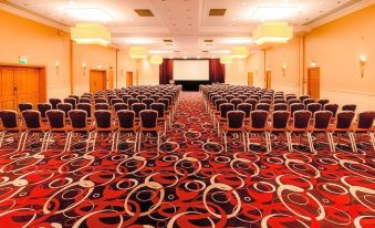 a large conference room with rows of chairs and a projector screen at the front at The Park Royal Hotel & Spa