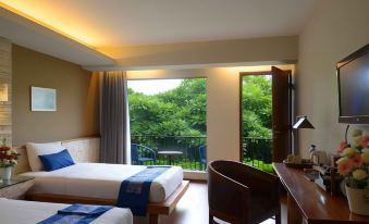 a hotel room with two beds , a desk , and a window looking out onto a green landscape at Rumah Batu Boutique Hotel