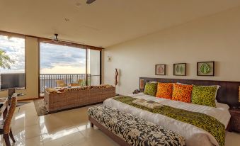 a spacious bedroom with a large bed and a sliding glass door leading to a balcony at Sankara Hotel & Spa Yakushima