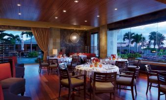 a well - decorated restaurant with wooden floors , large windows , and multiple dining tables set for guests at Four Seasons Resort Maui at Wailea
