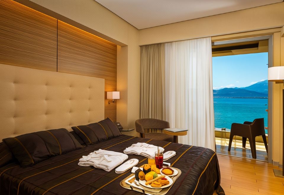 a luxurious hotel room with a king - sized bed , a dining table , and a balcony overlooking the ocean at Nafs Hotel