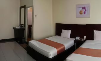 a modern hotel room with two beds , a desk , and an air conditioner , decorated in neutral colors at Jazz Hotel Palu