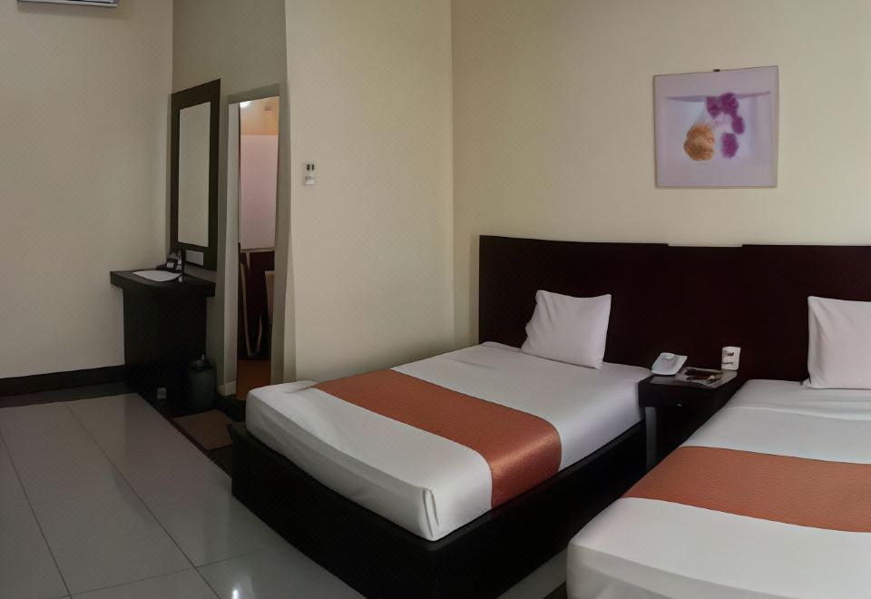 a hotel room with two beds , one on the left and one on the right side of the room at Jazz Hotel Palu