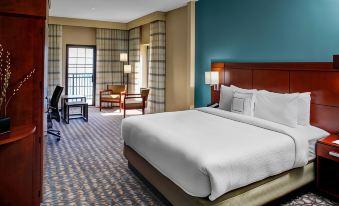 a hotel room with a king - sized bed , a dining table , and a balcony overlooking the ocean at Courtyard New Bern