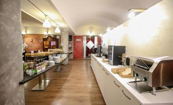 a modern kitchen with wooden flooring , white cabinets , and various appliances and utensils on the counter at Hotel Diplomatic