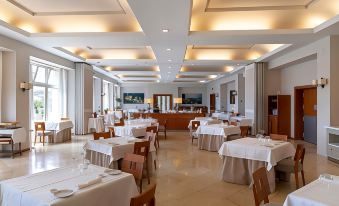 a large , well - lit dining room with tables and chairs arranged for a group of people at Parador de Javea