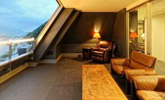 a modern living room with a large window offering a view of the sea , leather furniture , and a wooden coffee table at Mizno Hotel