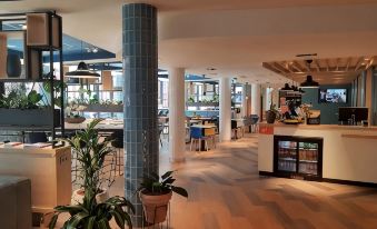 a large , well - lit restaurant with multiple dining tables and chairs , as well as an outdoor area where people are enjoying their meals at Hampton by Hilton Antwerp Central Station